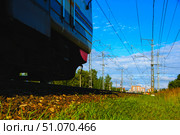 A train with a red stripe on the body is moving along the rails. Russia. Moscow oblast. 14.08. 2025. Редакционное фото, фотограф Ярославский Максим / Фотобанк Лори