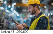 Construction worker checks data on tablet in a busy manufacturing facility with modern equipment and bright lighting. Стоковое AI-видео, аниматор Сергей Толмачёв / Фотобанк Лори