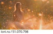 A woman practices meditation in a forest at sunset, surrounded by sparkling lights. Стоковое AI-видео, аниматор Данила Большаков / Фотобанк Лори