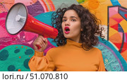 A woman with curly hair shouts into a megaphone while standing in front of a vibrant, colorful wall. Стоковое AI-видео, аниматор Данила Большаков / Фотобанк Лори