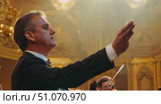 A conductor directs a symphony orchestra in a performance. Стоковое AI-видео, аниматор Данила Большаков / Фотобанк Лори