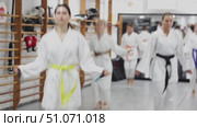 Young woman in a kimono with a black belt jumps rope, she does a warm-up before training. Woman at group karate training. Стоковое видео, видеограф Яков Филимонов / Фотобанк Лори