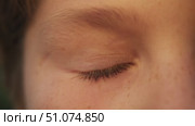 A close-up of the brown eyes of a young man with freckles on his nose, who is squinting in the sunlight and gazing at the camera. Стоковое видео, видеограф Strunov David / Фотобанк Лори