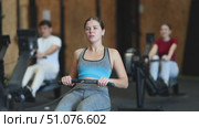 Woman performs exercises on a rowing machine, keeping the pace. Athletic woman in crossfit training doing intense exercises. Client in the gym monitors the figure and goes to training. Стоковое видео, видеограф Яков Филимонов / Фотобанк Лори