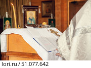 A priest holds a book for reading prayers during the rite of baptism in the Orthodox Church. Стоковое фото, фотограф Екатерина Красникова / Фотобанк Лори