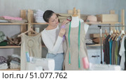 Asian woman working as a dressmaker in a workshop and sewing clothes to order, she tries on a sample on a mannequin. Стоковое видео, видеограф Яков Филимонов / Фотобанк Лори