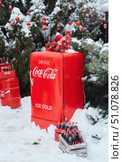 Krasnodar, Russia - December 10, 2021: Coca-Cola refrigerator on the street during snow and various products of this company. A photo zone for creating a Christmas mood. Редакционное фото, фотограф Наталия Кирсанова / Фотобанк Лори