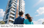 Пара с надеждой смотрит на новостройку / The couple looks hopefully at the new building. Стоковое AI-изображение, AI-художник Валерий Лукин / Фотобанк Лори