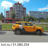 Авто Яндекс-такси жёлто-светло-коричневого цвета стоит на тротуаре на фоне городской магистрали. Редакционное фото, фотограф Клавдия Васильева / Фотобанк Лори