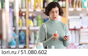 Selective middle-aged female customer choosing convenient nail polish in retail store. Стоковое видео, видеограф Яков Филимонов / Фотобанк Лори