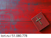Vintage red-painted wooden bible box with handcrafted cross symbol placed against distressed red wooden planks background featuring weathered blue undertones and natural wood grain patterns. Religious faith concept. Стоковое AI-изображение, AI-художник Лариса Пономарева / Фотобанк Лори