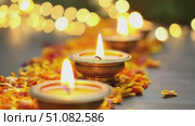 Three glowing diya lamps on a bed of marigold petals. Soft bokeh lights in the background. Represents Diwali, the festival of lights, and traditional Hindu celebrations. Стоковое AI-видео, аниматор Nart / Фотобанк Лори