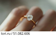 Close-up of a hand wearing a gold engagement ring with a large, round diamond. The background is softly blurred, emphasizing the ring's details. Стоковое AI-видео, аниматор Nart / Фотобанк Лори