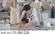 Young skilled dressmaker drawing garment pattern and using curved rulers, she designs clothing sketch before sewing. Стоковое видео, видеограф Яков Филимонов / Фотобанк Лори