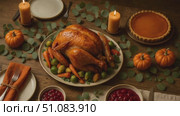 A beautifully arranged Thanksgiving dinner featuring a roasted turkey, cranberry sauce, pumpkin pie, and decorative pumpkins on a wooden table. Стоковое AI-видео, аниматор Nart / Фотобанк Лори