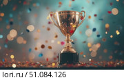 A shiny gold trophy stands on a black base. Colorful confetti falls around it, creating a festive atmosphere. The background is blurred with soft lights. Стоковое AI-видео, аниматор Nart / Фотобанк Лори