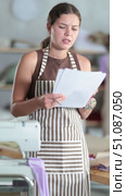 Upset seamstress girl reading financial document in sewing studio interior. Стоковое видео, видеограф Яков Филимонов / Фотобанк Лори