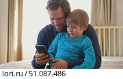 Father and son little boy laughing and using phone. They watching funny videos together, playing games on smartphone. Concept technology, smartphone addicted. Fun weekend activity. Modern fatherhood. Стоковое видео, видеограф Марина Демидюк / Фотобанк Лори