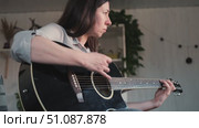 Woman Practicing Guitar in Cozy Room at Home. Strumming black acoustic guitar. Female learning to play music. Person hand on a guitar neck. Guitarist working on melody, performance, practice indoors. Стоковое видео, видеограф Марина Демидюк / Фотобанк Лори