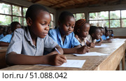 Children in an African classroom learning about geography, looking at maps and educational materials. Lack of school supplies. Black African children from disadvantaged families learn in school, read books, get primary education, volunteer service. Стоковое AI-изображение, AI-художник ALLA YURTAYEVA / Фотобанк Лори