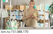 Attentive pregnant woman holding baby food trying to make choice in chemist's shop. Стоковое видео, видеограф Яков Филимонов / Фотобанк Лори