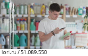 Male shopper checks a QR code on a dishwashing sponge label in a supermarket. Стоковое видео, видеограф Яков Филимонов / Фотобанк Лори
