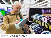 senor man pensioner buying iron in showroom of electrical appliance store. Стоковое фото, фотограф Татьяна Яцевич / Фотобанк Лори