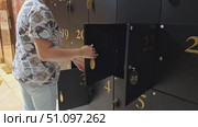 Unlocking black locker, woman accesses secure storage in modern setting. Стоковое видео, видеограф Zakharova Natasha / Фотобанк Лори