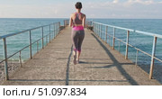 Woman jogging along concrete pier towards open sea morning sunlight, slow motion capturing fitness, freedom and coastal workout energy. Effect of blocked stabilization. LOCKED-ON STABILIZATION EFFECT. Стоковое видео, видеограф Сергей Тимофеев / Фотобанк Лори