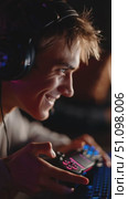Young gamer smiling while playing in a competitive eSports environment at night with friends nearby. Стоковое AI-видео, аниматор Сергей Толмачёв / Фотобанк Лори