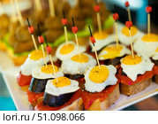 Small canapé sandwiches made from circle of fried black pudding and fried egg are prepared for feast. Стоковое фото, фотограф Яков Филимонов / Фотобанк Лори