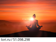 Silhouette of woman in lotus yoga pose meditating on hill top at sunrise, concept for mindfulness and spiritual practice. Стоковое фото, фотограф Павел Муравьев / Фотобанк Лори