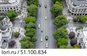 Busy urban avenue lined with trees and bustling pedestrians in a city. Стоковое AI-изображение, AI-художник Katsiaryna Repich / Фотобанк Лори