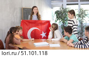Decent teacher showing Turkey flag to group of preteen schoolchildren in classroom during lesson. Стоковое видео, видеограф Яков Филимонов / Фотобанк Лори