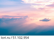Beautiful pastel-colored sunset illuminating majestic mountain peaks through a layer of clouds, creating a breathtaking and serene natural landscape. Стоковое фото, фотограф Ольга Ильина / Фотобанк Лори