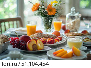 Fresh fruit, juice, and pastries arranged on a table create a healthy and inviting breakfast setting. Стоковое AI-изображение, AI-художник Иван Рябоконь / Фотобанк Лори