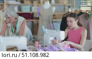 Elderly dressmaker teaches a course of cutting and sewing in a workshop. Стоковое видео, видеограф Яков Филимонов / Фотобанк Лори
