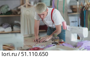 Attentive young male dressmaker drawing dress design on paper using curves in sewing workshop. Стоковое видео, видеограф Яков Филимонов / Фотобанк Лори