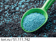 Green scoop with fertilizer blue granules. Granular chemical fertiliser for plant over soil background. Role of nutrients mineral in plants growth, soil life. Space for text. Gardening time. Planting. Стоковое AI-изображение, AI-художник Марина Демидюк / Фотобанк Лори