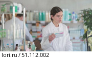 Woman pharmacist uses computer at workplace. Man assistant in background. Стоковое видео, видеограф Яков Филимонов / Фотобанк Лори