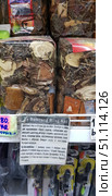 Shelves in a Thai store with the medicinal herbal collection Ya Bamrung Rang Kai. Transparent plastic bags are filled with a mixture of dried plants, roots and bark. The packaging has a label with a description of the composition and method of application. The instructions indicate that the collection consists of 30 herbs for the preparation of a tincture that helps normalize metabolism, stabilize blood pressure, relieve chronic fatigue syndrome, cleanse the kidneys, restore the body after illnesses and operations, and cleanse blood vessels of cholesterol. Below is a detailed description of the preparation method and dosage: infusion in vodka with honey for 7-10 days.The photo shows characteristic pieces of bark, wood elements and crushed herbs. In the foreground, a paper instruction in Russian is attached. Price tags are visible on the right and left, and other store products are partially visible in the background.The image is great for illustrating topics related to traditional medicine, herbal infusions, natural treatment and exotic healing products from Thailand. (2018 год). Редакционное фото, фотограф Анна Кривицкая / Фотобанк Лори