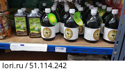 A shelf in a store with bottles of Noni Juice, a popular natural product from Thailand. The shelf contains different brands - in rectangular plastic bottles and in round glass containers of 500 ml with white labels and lids. The labels depict noni fruits, as well as inscriptions in English, Thai and Russian. Noni juice is known as a dietary supplement used to strengthen the immune system, improve metabolism, maintain the cardiovascular system and improve overall health. Under the shelf is a paper sign with the price. The atmosphere of a local Thai store with natural drinks and health products. (2018 год). Редакционное фото, фотограф Анна Кривицкая / Фотобанк Лори