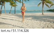 Smiling woman in bikini walks on white sand beach under palm trees by turquoise water. Стоковое видео, видеограф Ольга Сухарева / Фотобанк Лори