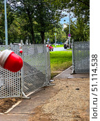 A red and white lamp is thrown over the fence. This is the fencing of the repair site on the street. Russia. Moscow. 19.08.25. Редакционное фото, фотограф Ярославский Максим / Фотобанк Лори