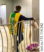 A man in a Metro vest stands on the railing with a newspaper. He distributes a free newspaper to the passengers. Russia. Moscow. 19.08.25. Редакционное фото, фотограф Ярославский Максим / Фотобанк Лори