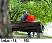 A couple is sitting on a park bench enjoying each other's company. rt, and the woman is wearing a red jacket. Russia. Moscow. 19.08.25. Редакционное фото, фотограф Ярославский Максим / Фотобанк Лори