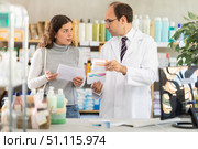 Experienced pharmacist helps girl buy medicine - he reads the prescription and compares it with data on computer. Стоковое фото, фотограф Яков Филимонов / Фотобанк Лори