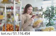 Checking expiration date of chips - female shopper scans QR code on label of chips using her smartphone. Стоковое видео, видеограф Яков Филимонов / Фотобанк Лори