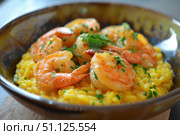 Saffron risotto with grilled shrimps and parsley in a bowl. Стоковое AI-изображение, AI-художник Иван Рябоконь / Фотобанк Лори