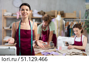 Young female dressmaker inviting clients while others sew and draw. Стоковое фото, фотограф Яков Филимонов / Фотобанк Лори